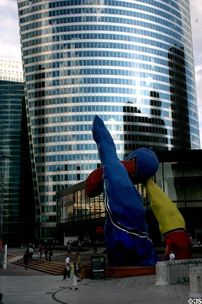 EDF building which is wider at top than bottom beyond Fantastic characters sculpture (1977) by Joan Miró at La Défense. Paris, France.
