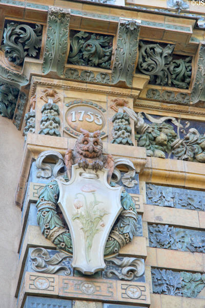 Detail of upper left corner with 1753 roots date of Sevres factory over owl & plaque with poppies on Sevres Arch at St-Germain-des-Prés. Paris, France.