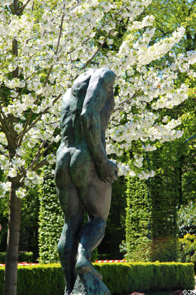 Bronze sculpture by Auguste Rodin with fruit tree blossoms at Rodin Museum Garden. Paris, France.