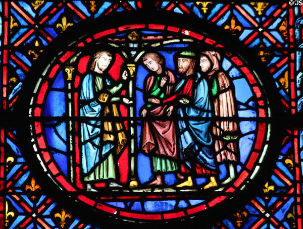 Man in arch with three men stained glass scene at St Chapelle. Paris, France.