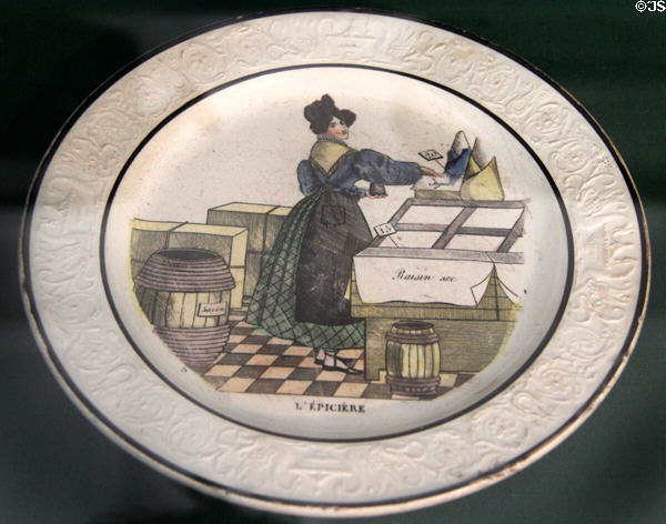 The Grocer (c1830) one of a set of plates decorated with food shopping scenes, Choisy-le-Roi fine earthenware made by Valentin Paillart & Hippolyte Hautin at Carnavalet Museum. Paris, France.