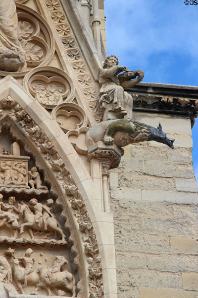 Beast-like gargoyle & violin player on Reims Cathedral. Reims, France.