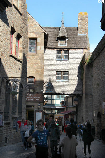 Visitors strolling past old houses (15-16thC) along Grande Rue. Mont-St-Michel, France.