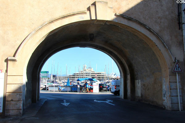 View through city gate to harbor & mega-yacht. Antibes, France.