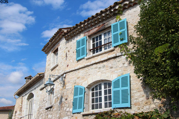 Rough stone building with blue shutters & tile roof. St Paul de Vence, France.