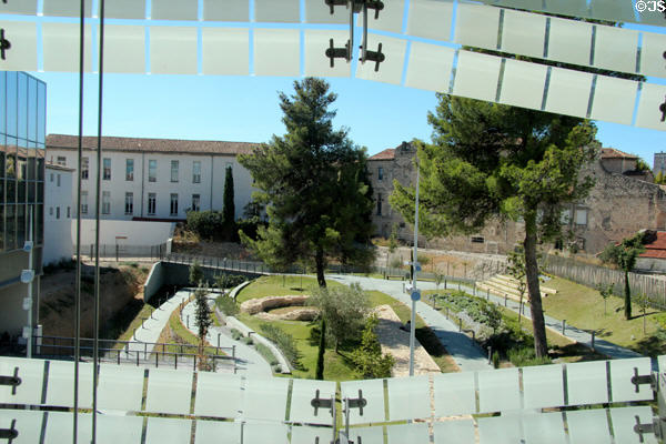 Landscaped courtyard park seen through window of Musée de la Romanité. Nimes, France.