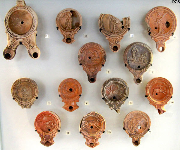 Roman-era ceramic oil lamps with molded decorative scenes (c1stC) mostly found in Rhone River at Arles Antiquities Museum. Arles, France.