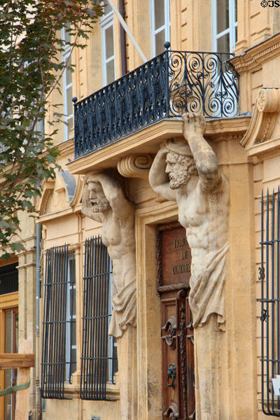 Sculpted figures hold up balcony in narrow streets of old Aix. Aix-en-Provence, France.