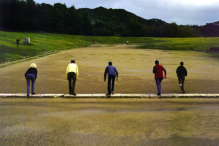 Tourists race from starting line in original Olympic stadium in Olympia. Greece.