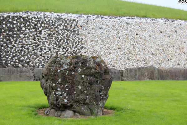 Newgrange standing stone against black & white wall of passage tomb. Ireland.