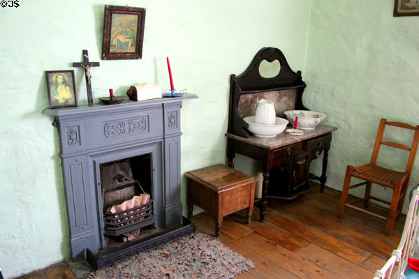 Fireplace & wash stand in bedroom at Quille's farm at Muckross Traditional Farms in Killarney National Park. Killarney, Ireland.