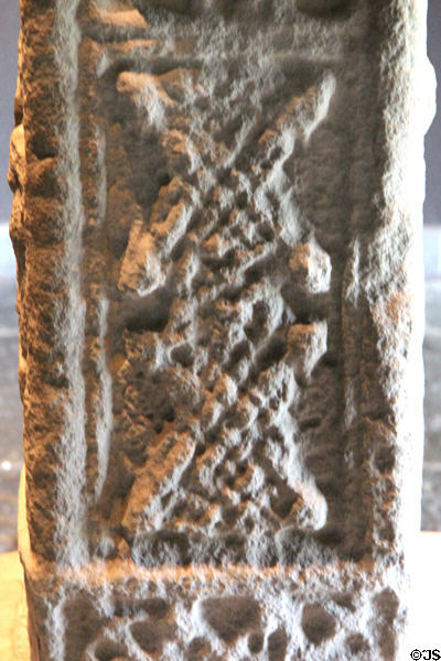 Lace with eight human heads detail on Cross of Scriptures (south edge) at Clonmacnoise museum. Ireland.