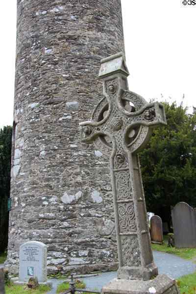 Celtic cross at base of round tower at Glendalough. Ireland.