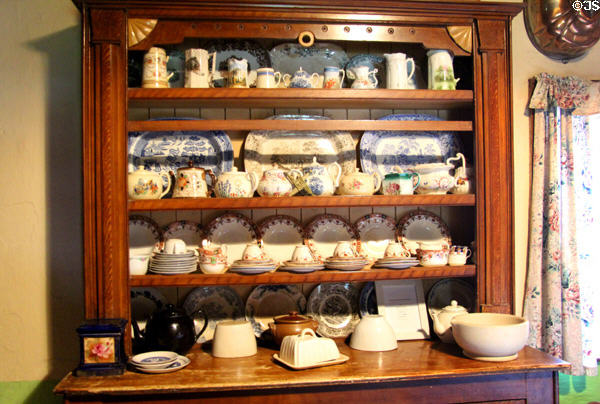 Open wooden cupboard with dishes in Golden Vale Farmhouse at Bunratty Castle & Folk Park. County Clare, Ireland.