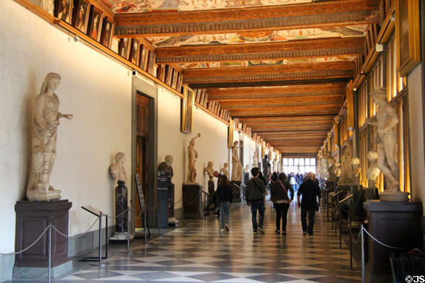 East corridor with windows over courtyard with statues collected by the Medici family in the 16th & 17th centuries at Uffizi Gallery. Florence, Italy.