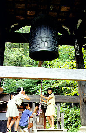 Children ringing a bronze bell in a Hida Folk Village, Takayama. Japan.