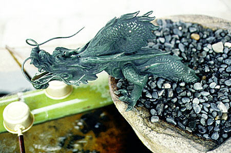 Small dragon emerging from rocks of fountain at temple in Kyoto. Japan.