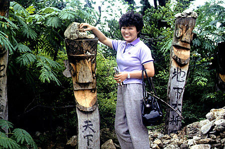 Placing stone on head of totem which is request for good luck or fertility in folk village, Seoul. South Korea.