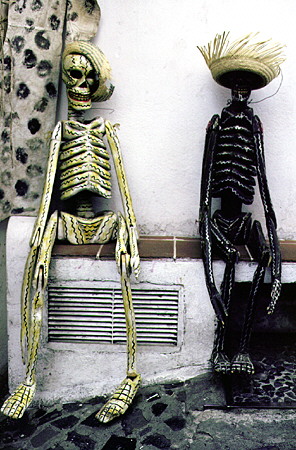 Two artistic skeletons sit on a wall in Taxco. Mexico.