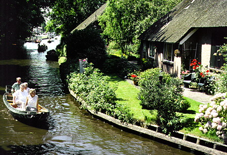 Canal cruising behind houses. Giethoorn, Netherlands.