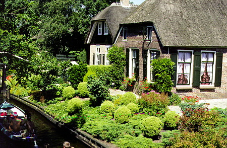Lush gardens beside the river. Giethoorn, Netherlands.