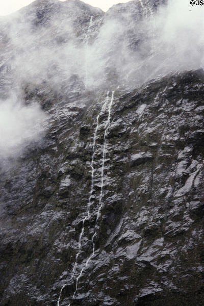 Waterfall trickles down rocks near Milford Sound. New Zealand.