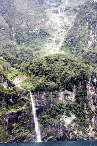 Rocky cliff and waterfall plunges into Milford Sound. New Zealand.