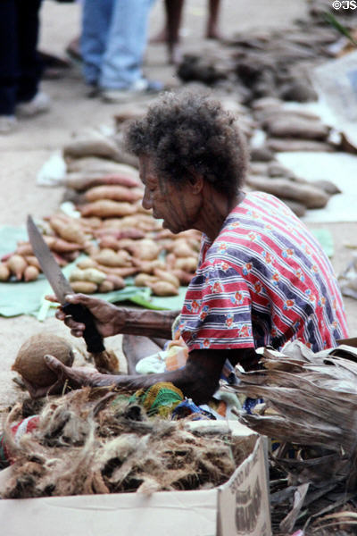 Cutting the husks off coconuts in Port Moresby market. Papua New Guinea.