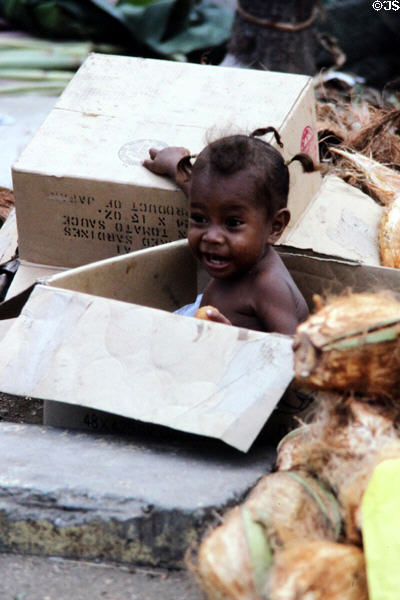Baby playing in boxes at the Port Moresby market. Papua New Guinea.