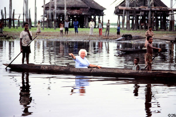 Elderly tourist takes a ride in a dugout canoe, Kambaramba. Papua New Guinea.