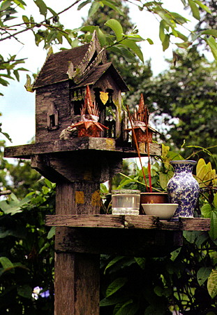 A traditional wooded Sala Chao shrine with an array of offerings in Chiang Mai. Thailand.