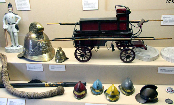 Model firemen's helmets & objects plus model fire pumper (c1830) at Museum of Edinburgh. Edinburgh, Scotland.