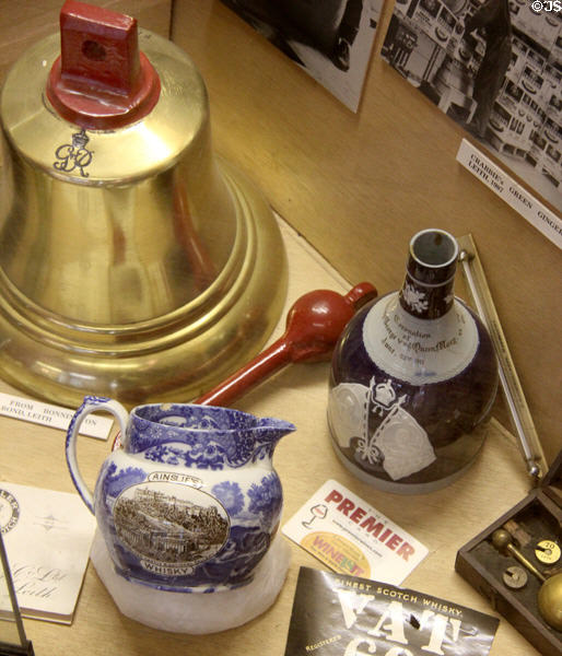 Ceramic whisky pitcher & bottle beside bell at People's Story Museum. Edinburgh, Scotland.