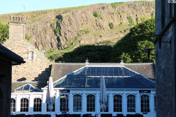 Holyrood Palace cafe building with glass roof against Salisbury Crags volcanic rock formation of Arthur's Seat. Edinburgh, Scotland.