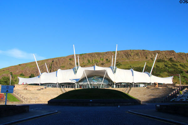 Our Dynamic Earth (1999) fabric membrane stretched over steel skeleton seen against Salisbury Crags volcanic formation. Edinburgh, Scotland. Architect: Michael Hopkins.