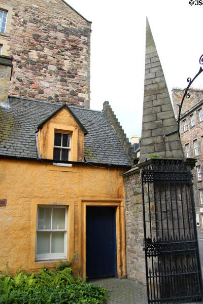 Yellow heritage house behind gate with pyramidal post near Canongate on Royal Mile. Edinburgh, Scotland.