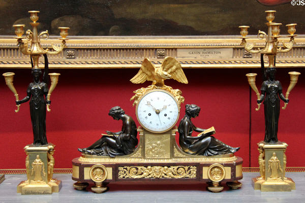 French drum mantle clock topped by eagle with torches & flanked by man & woman reading plus two candelabras at National Gallery of Scotland. Edinburgh, Scotland.