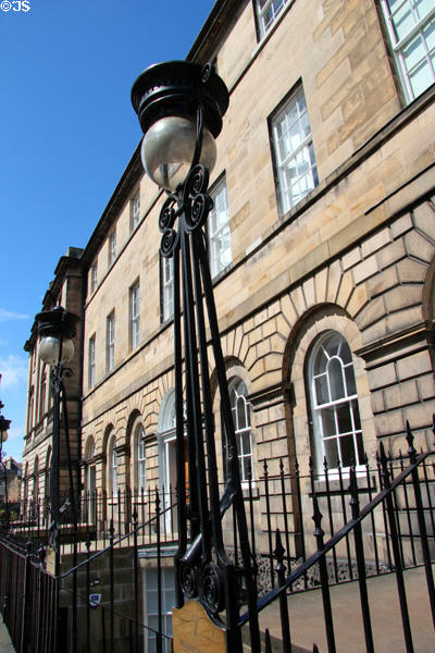 Georgian row houses on Charlotte Square with lamps & iron railings around basement service entrances. Edinburgh, Scotland.