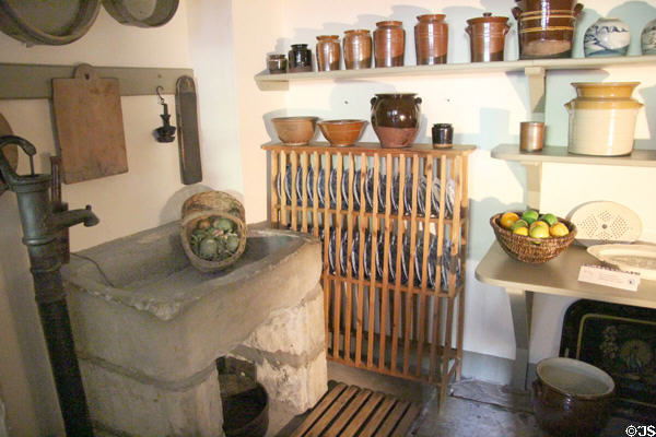 Pump & stone washing sink beside wooden dish rack & stoneware crocks in kitchen at Georgian House museum. Edinburgh, Scotland.