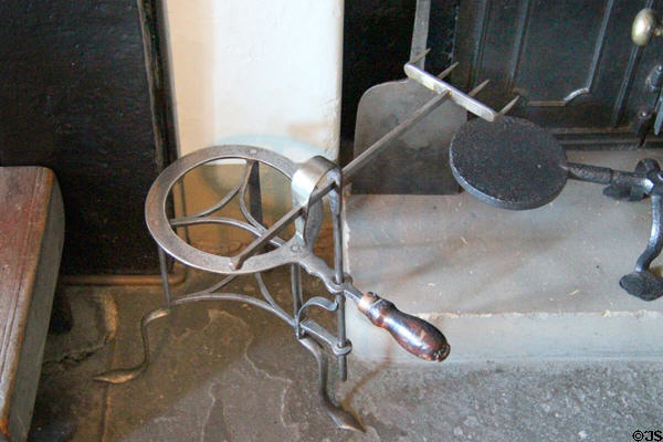 Metal trivet for kettle with attached roasting fork beside kitchen fireplace at Georgian House museum. Edinburgh, Scotland.