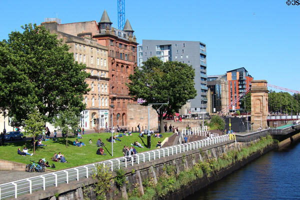 Clyde River in core with triumphal arch pylon of Clyde & South Portland footbridge with heritage office blocks (late 1800s). Glasgow, Scotland.