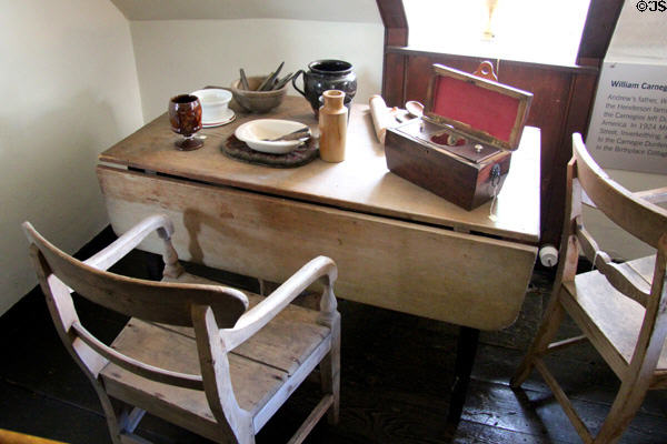 Table & chair with ceramics & tea chest at Andrew Carnegie Birthplace Museum. Dunfermline, Scotland.