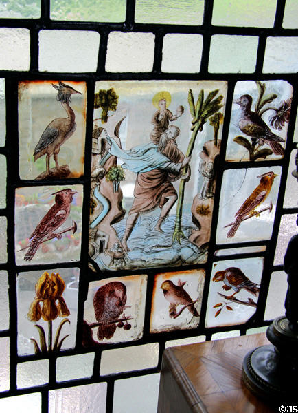 Stained glass inset of St Christopher crossing river with Jesus on his shoulder framed with insets of birds at Lauriston Castle. Edinburgh, Scotland.