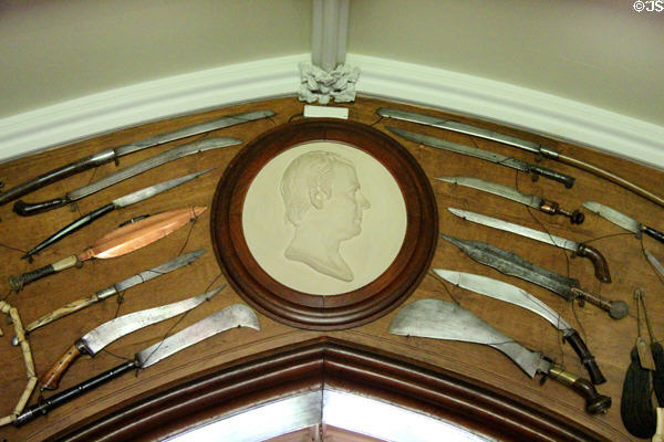 Swords & bladed weapons displayed around plaque of Sir Walter Scott in armory at Abbotsford House. Melrose, Scotland.