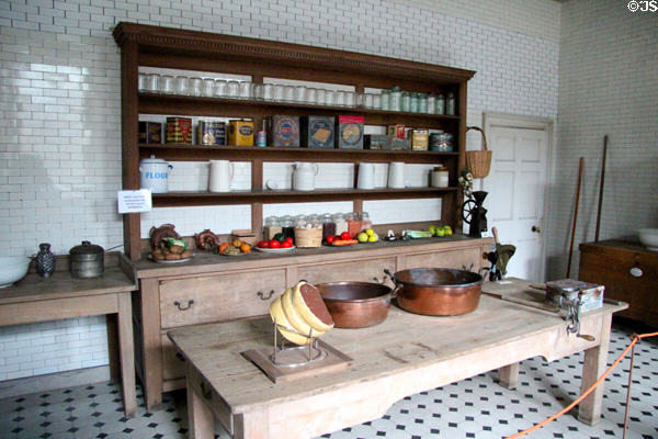 Food storage jars, tins & crocks on shelves beyond work table in kitchen at Manderston House. Duns, Scotland.