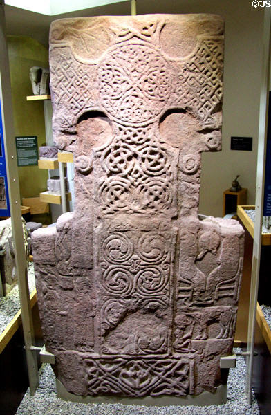 Pictish cross-slab (front figures stone) shows swirling patters on cross flanked by Christian figures at St Vigeans Museum. Arbroath, Scotland.