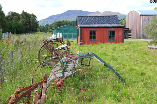 Horse-drawn harvesting machines with red railway waiting room beyond at Highland Folk Museum. Newtonmore, Scotland.