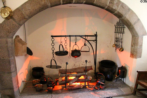 Kitchen fireplace with various metalware cookery items including flat bannock bread pans hanging from andiron at Crathes Castle. Crathes, Scotland.