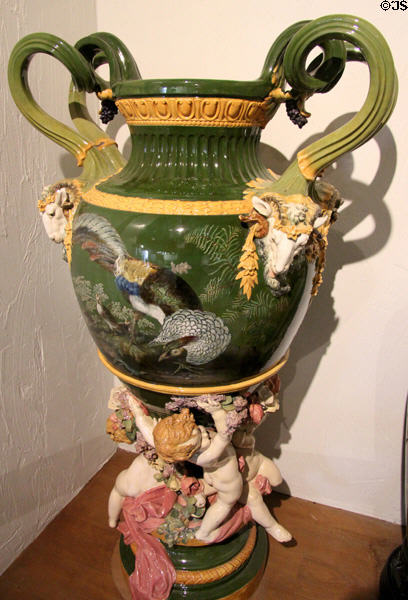 Earthenware scroll-handled vase sculpted with goats, exotic birds & supported by cupids (c1850s) by Albert Ernest Carrier de Belleuse for Minton of Stoke-upon-Trent at Potteries Museum & Art Gallery. Hanley, Stoke-on-Trent, England.