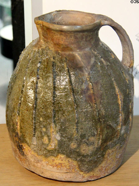 Red earthenware jug with copper stained glaze (1250-1300) made at Audlem, Cheshire at Potteries Museum & Art Gallery. Hanley, Stoke-on-Trent, England.